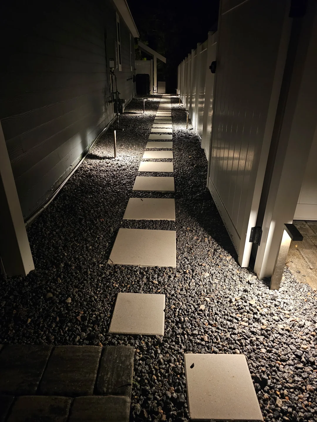 Stepping stones and path lights down a side yard