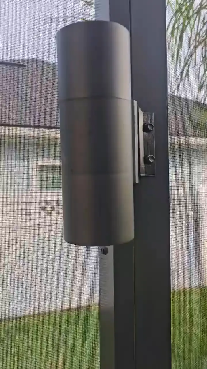 An up-down sconce and its mounting bracket on the enclosure frame, checked in daylight